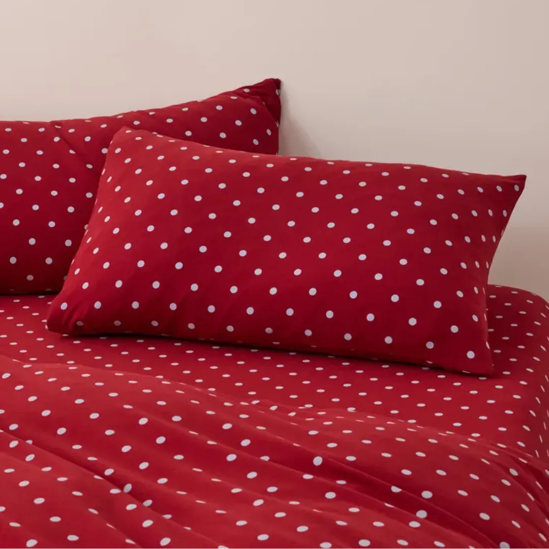 Two red polka dot pillows stacked on top of matching sheets from Sheet society