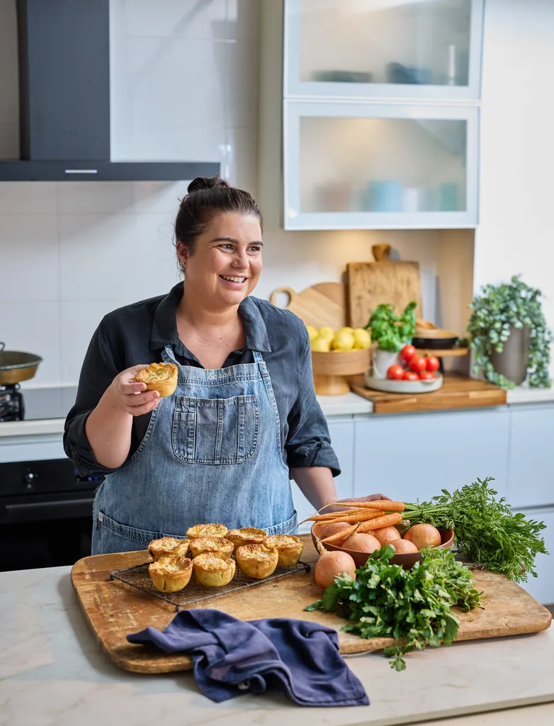 sarah murphy laughing holding her apricot chicken pies with pies in front of her on wooden chopping board