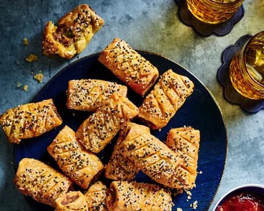 curry sausage rolls on blue plate with them all piled up with tomato relish on the side