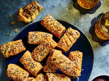curry sausage rolls on blue plate with them all piled up with tomato relish on the side