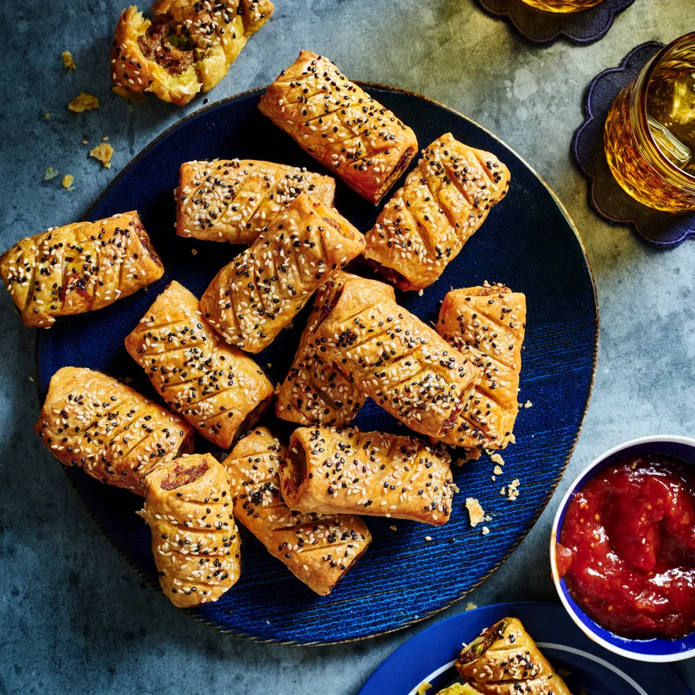 curry sausage rolls on blue plate with them all piled up with tomato relish on the side