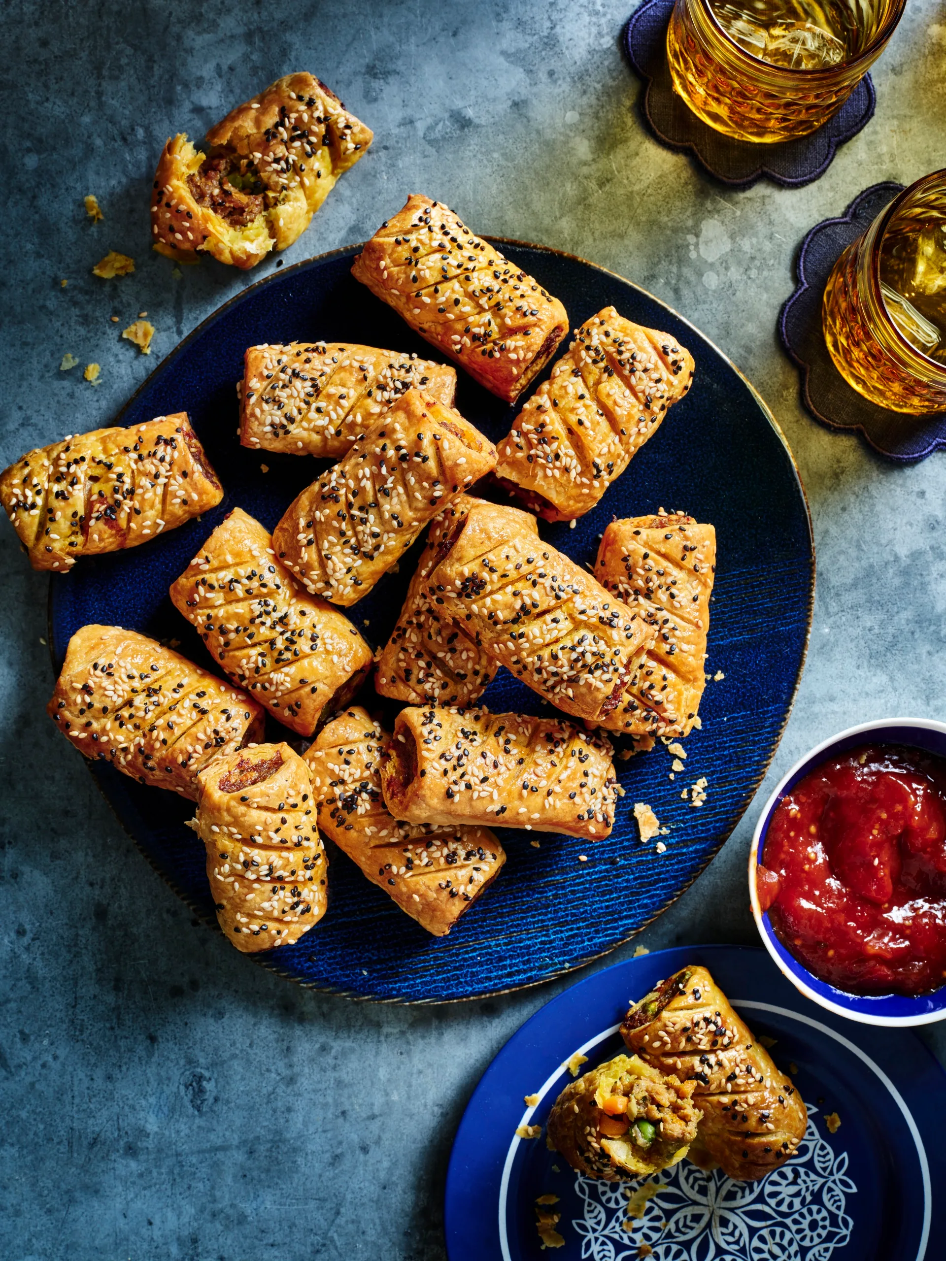 curry sausage rolls on blue plate with them all piled up with tomato relish on the side