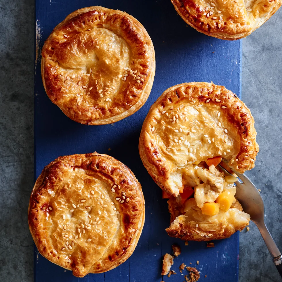 apricot chicken pies on blue tray with one crumbled showing the inside