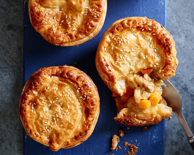 apricot chicken pies on blue tray with one crumbled showing the inside
