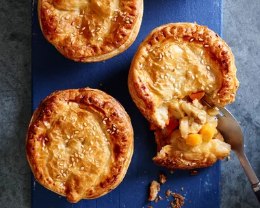 apricot chicken pies on blue tray with one crumbled showing the inside
