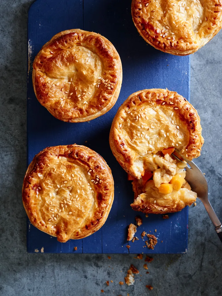apricot chicken pies on blue tray with one crumbled showing the inside