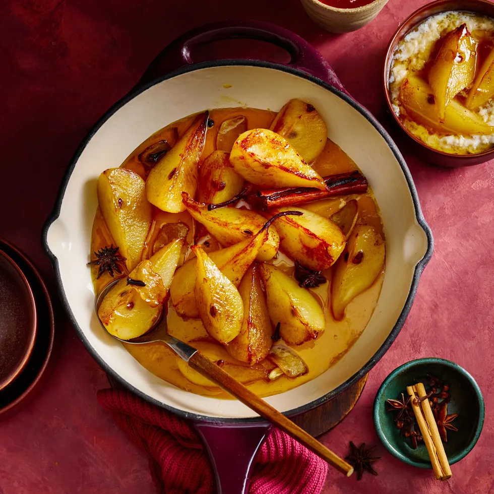 Spiced ginger pears in an enamelled cast-iron frying pan with a wooden spoon
