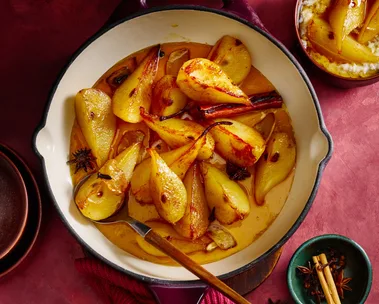 Spiced ginger pears in an enamelled cast-iron frying pan with a wooden spoon
