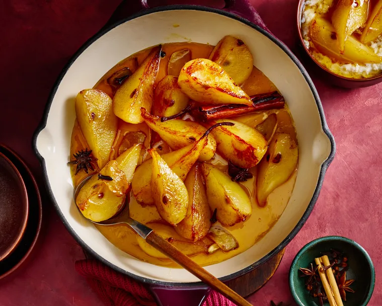 Spiced ginger pears in an enamelled cast-iron frying pan with a wooden spoon
