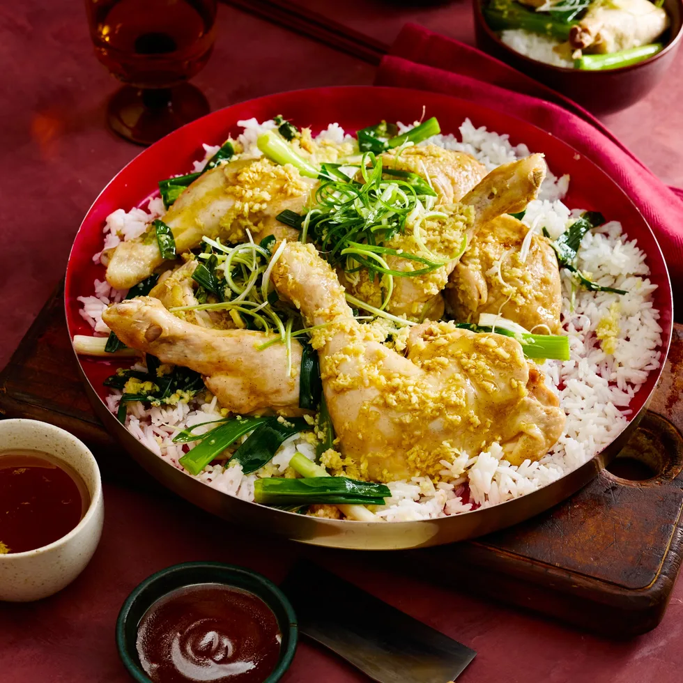 steamed ginger chicken marylands in red bowl on a bed of rice with herbs on top