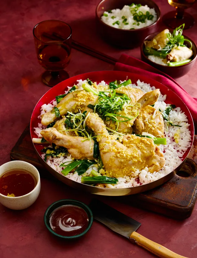 steamed ginger chicken marylands in red bowl on a bed of rice with herbs on top
