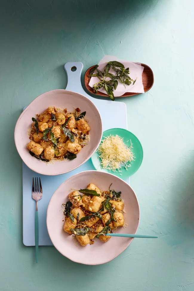 colin fassnidge's ricotta gnudi is on two white bowls with herbs sprinkled around them