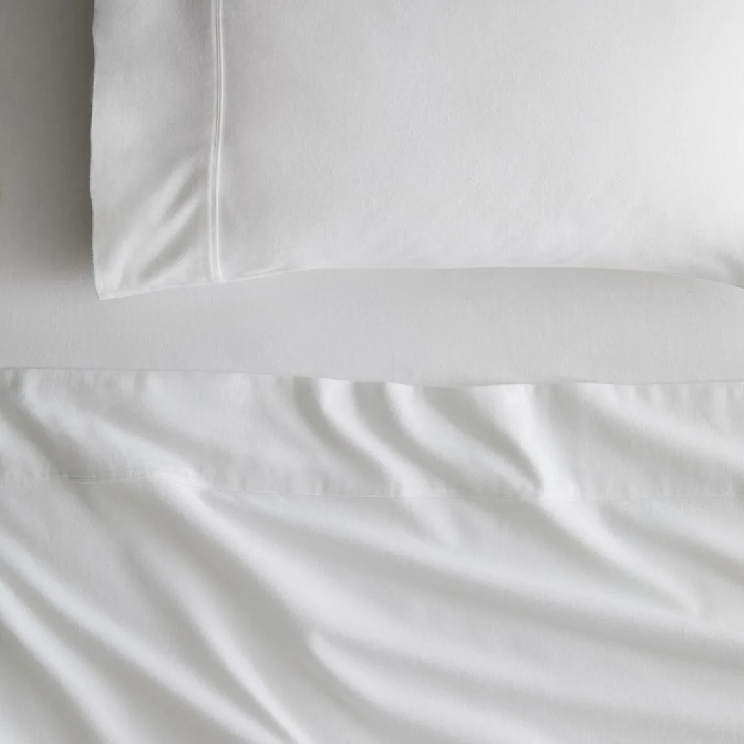 Top down image of a bed with a white flannelette fitted sheet, white flannelette top sheet and pillowcase from Sheridan
