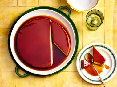 colin fassnidge's creme caramel cheesecake with slice cut out on separate plate sitting on bright tile like background