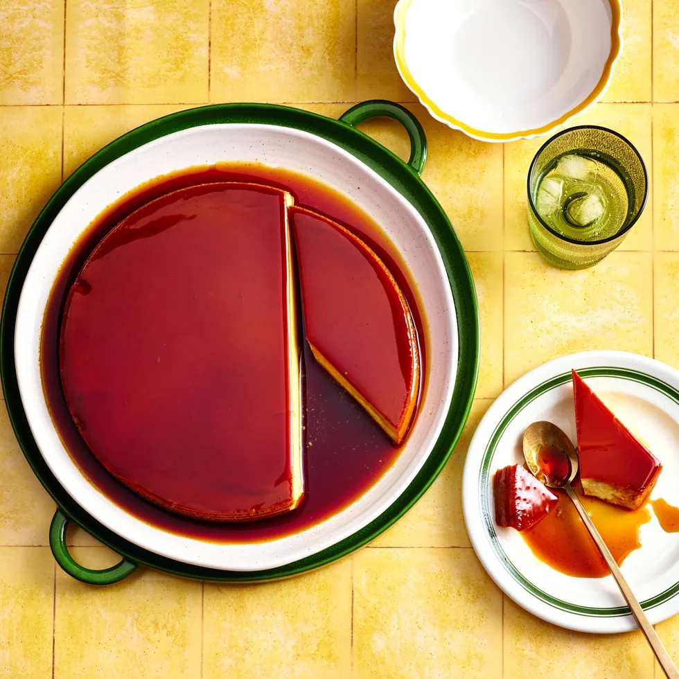 colin fassnidge's creme caramel cheesecake with slice cut out on separate plate sitting on bright tile like background