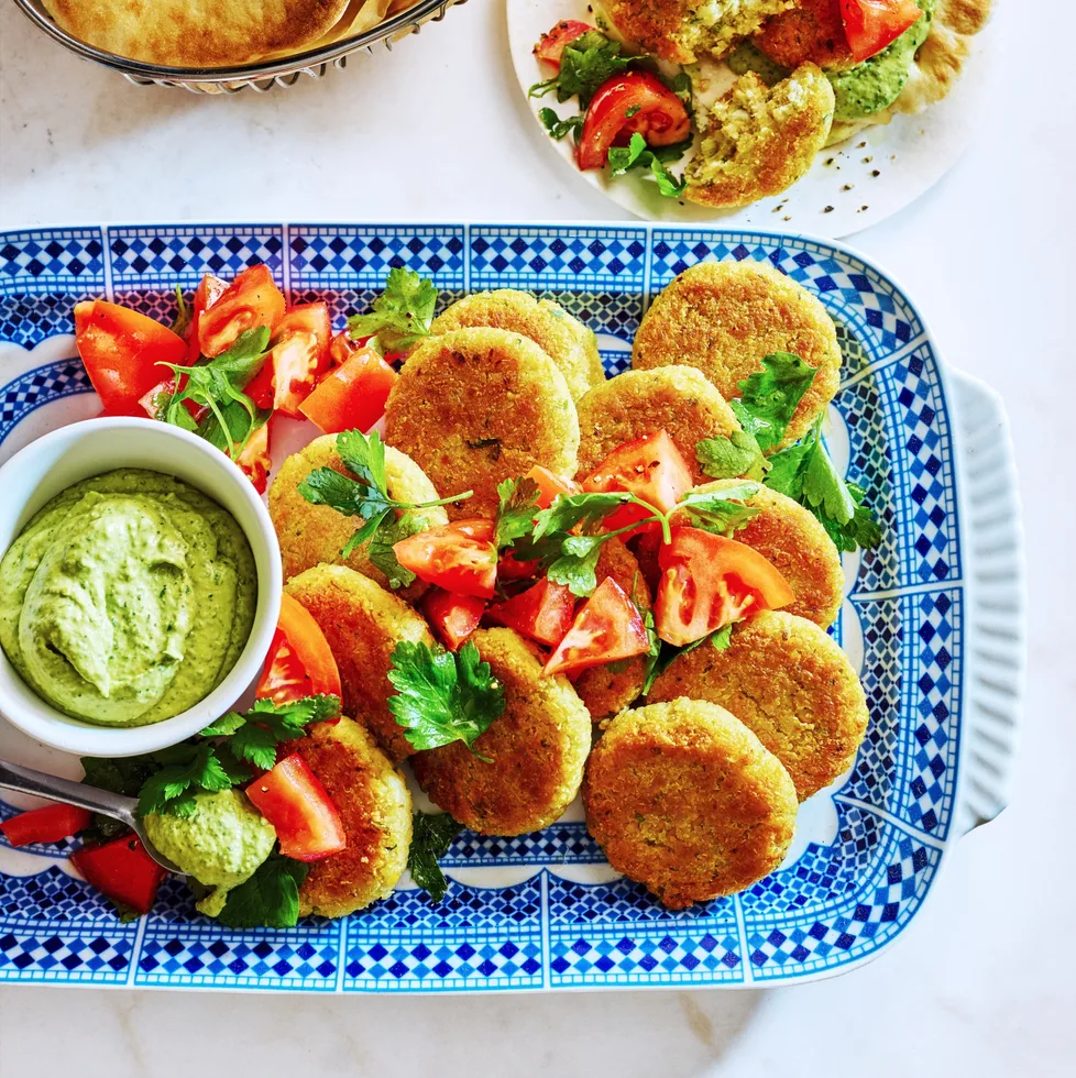quinoa falafel on tray with green hommus in small dipping bowl and tomato and parsley on top