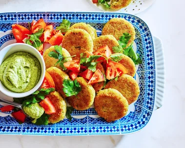 quinoa falafel on tray with green hommus in small dipping bowl and tomato and parsley on top