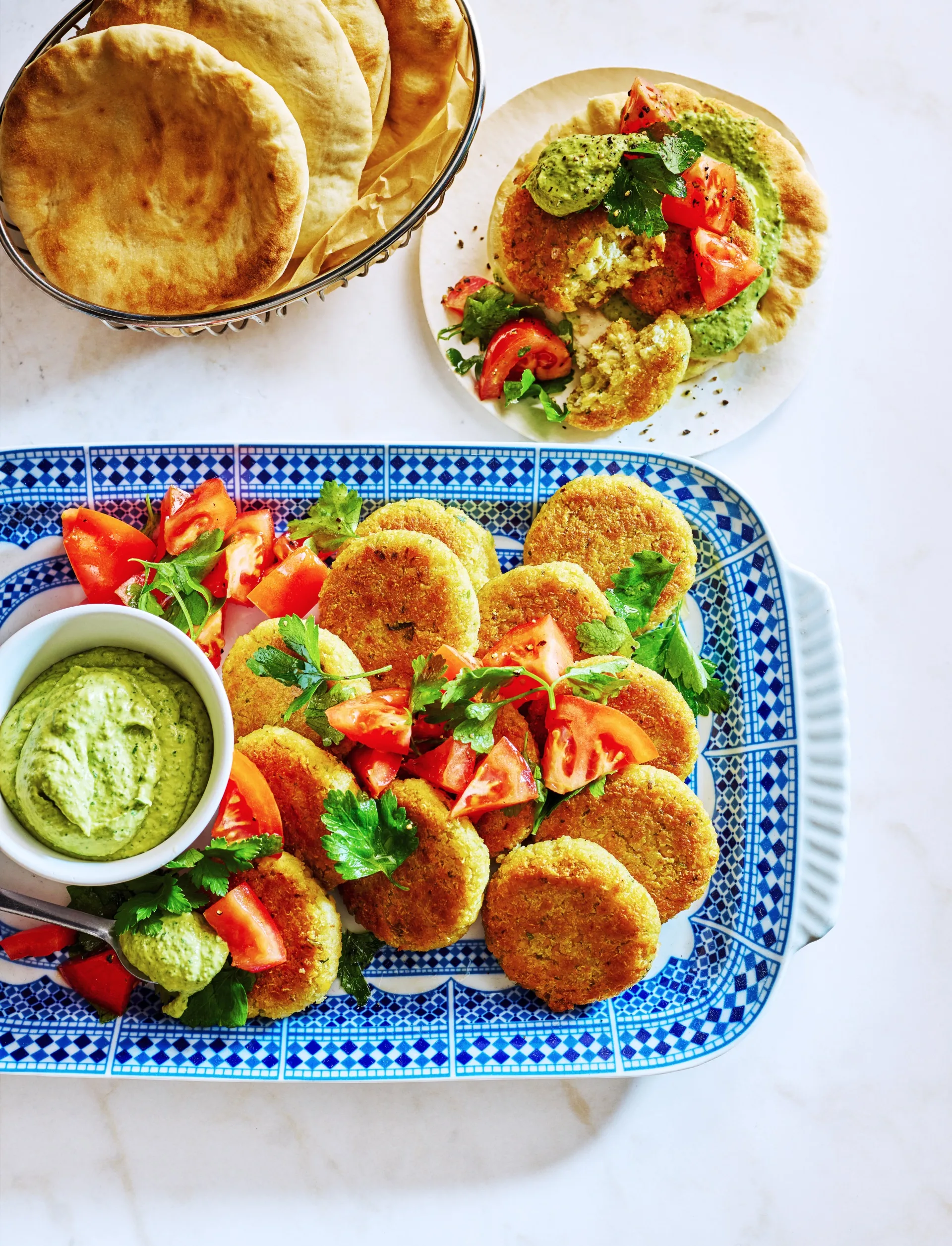 quinoa falafel on tray with green hommus in small dipping bowl and tomato and parsley on top