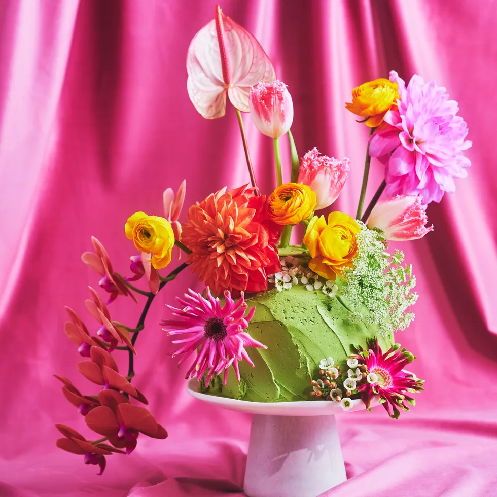 Pretty floral fantasy cake on a small white cake pedestal with a pink backdrop