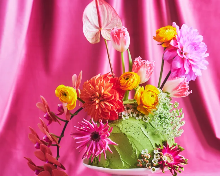 Pretty floral fantasy cake on a small white cake pedestal with a pink backdrop