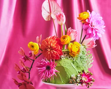 Pretty floral fantasy cake on a small white cake pedestal with a pink backdrop