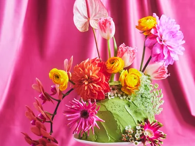 Pretty floral fantasy cake on a small white cake pedestal with a pink backdrop