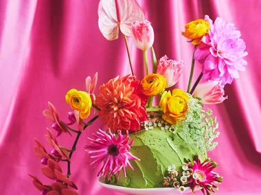 Pretty floral fantasy cake on a small white cake pedestal with a pink backdrop