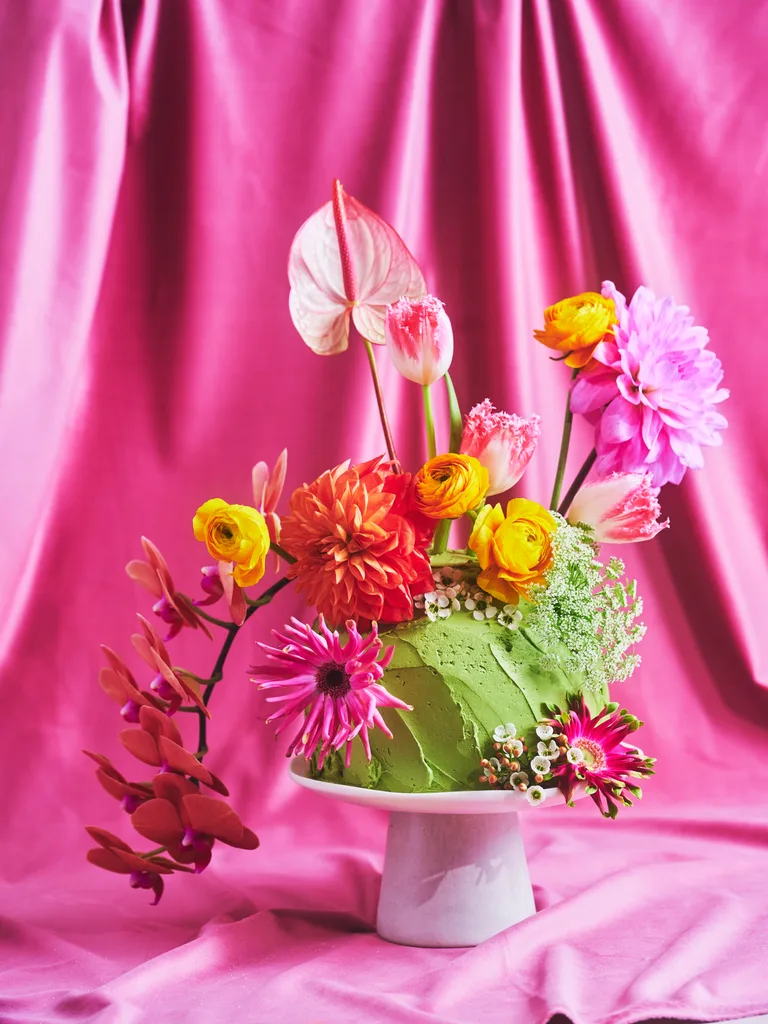 Pretty floral fantasy cake on a small white cake pedestal with a pink backdrop