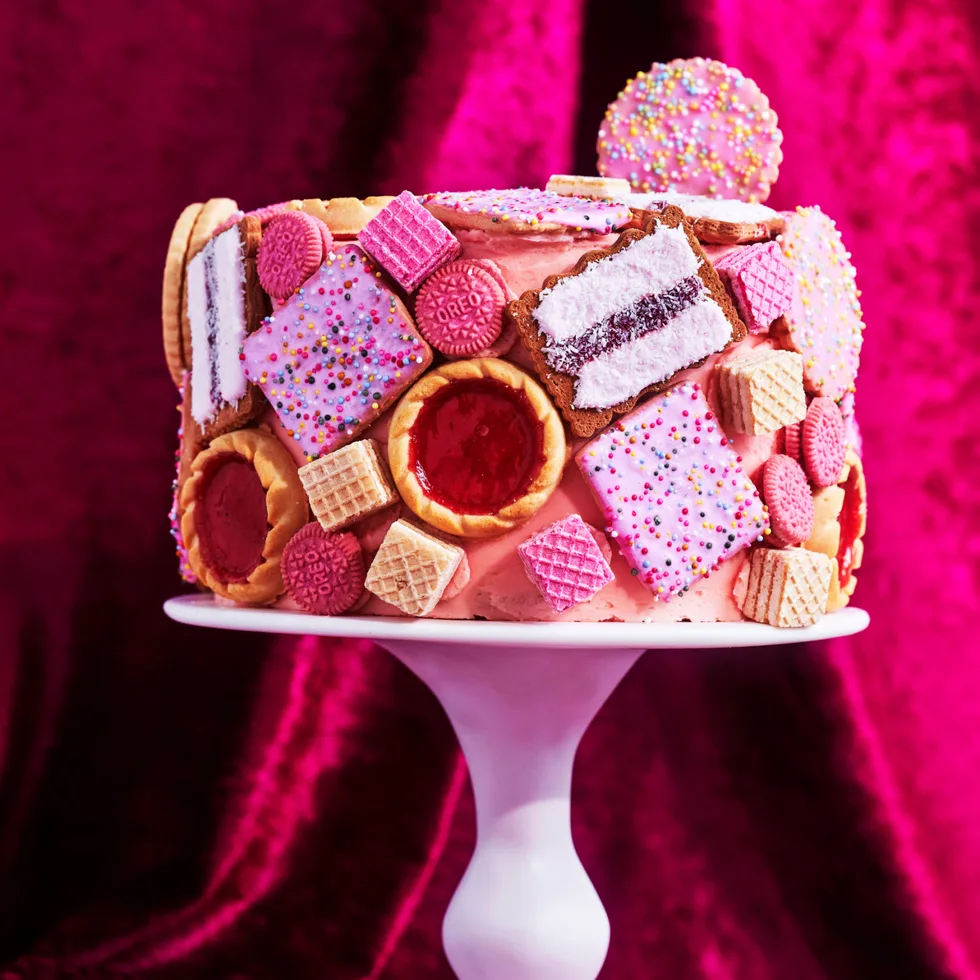 biscuit cake hack with pink icing and biscuit dotted over the cake