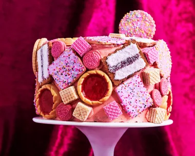 biscuit cake hack with pink icing and biscuit dotted over the cake