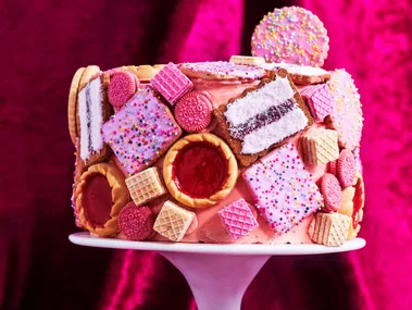 biscuit cake hack with pink icing and biscuit dotted over the cake
