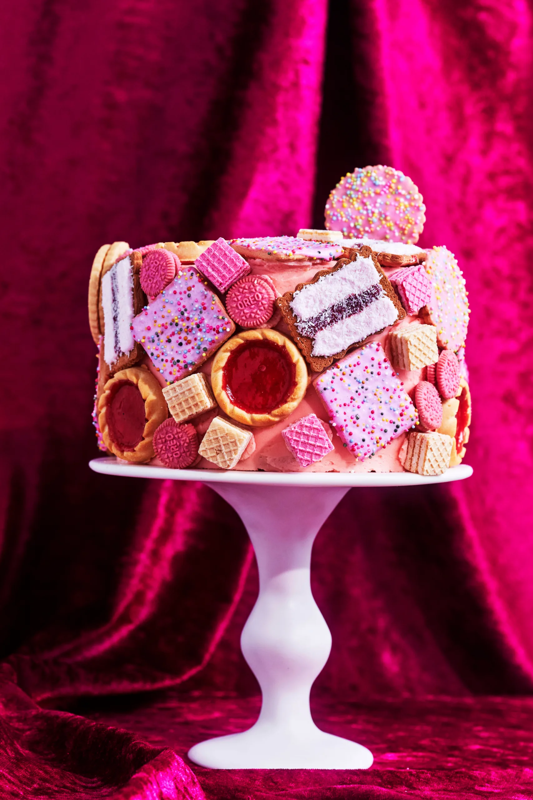 biscuit cake hack with pink icing and biscuit dotted over the cake
