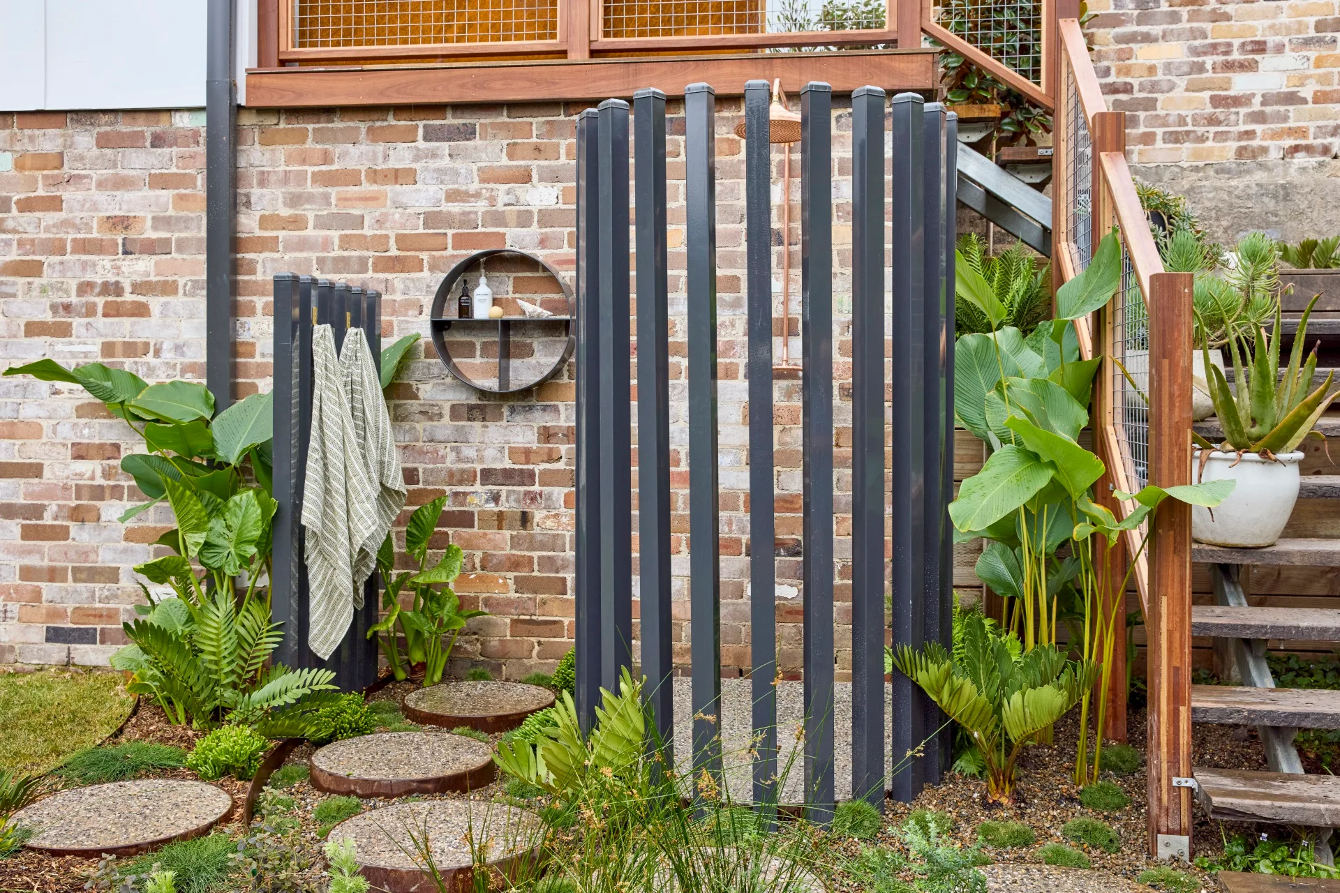 diy outdoor shower with metal casing and small shapescaper planters that are filled in to be stepping stones