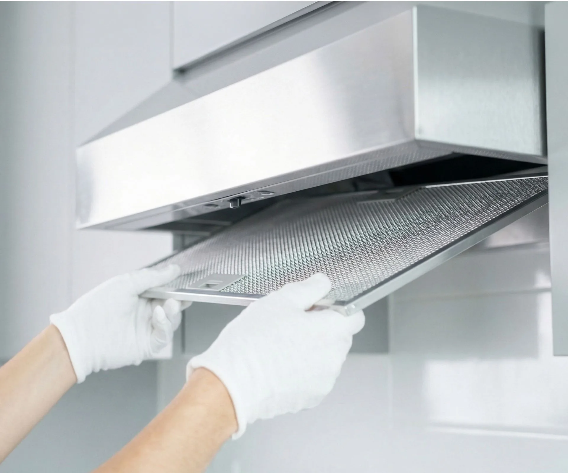 two hands with white gloves pulling down rangehood filters