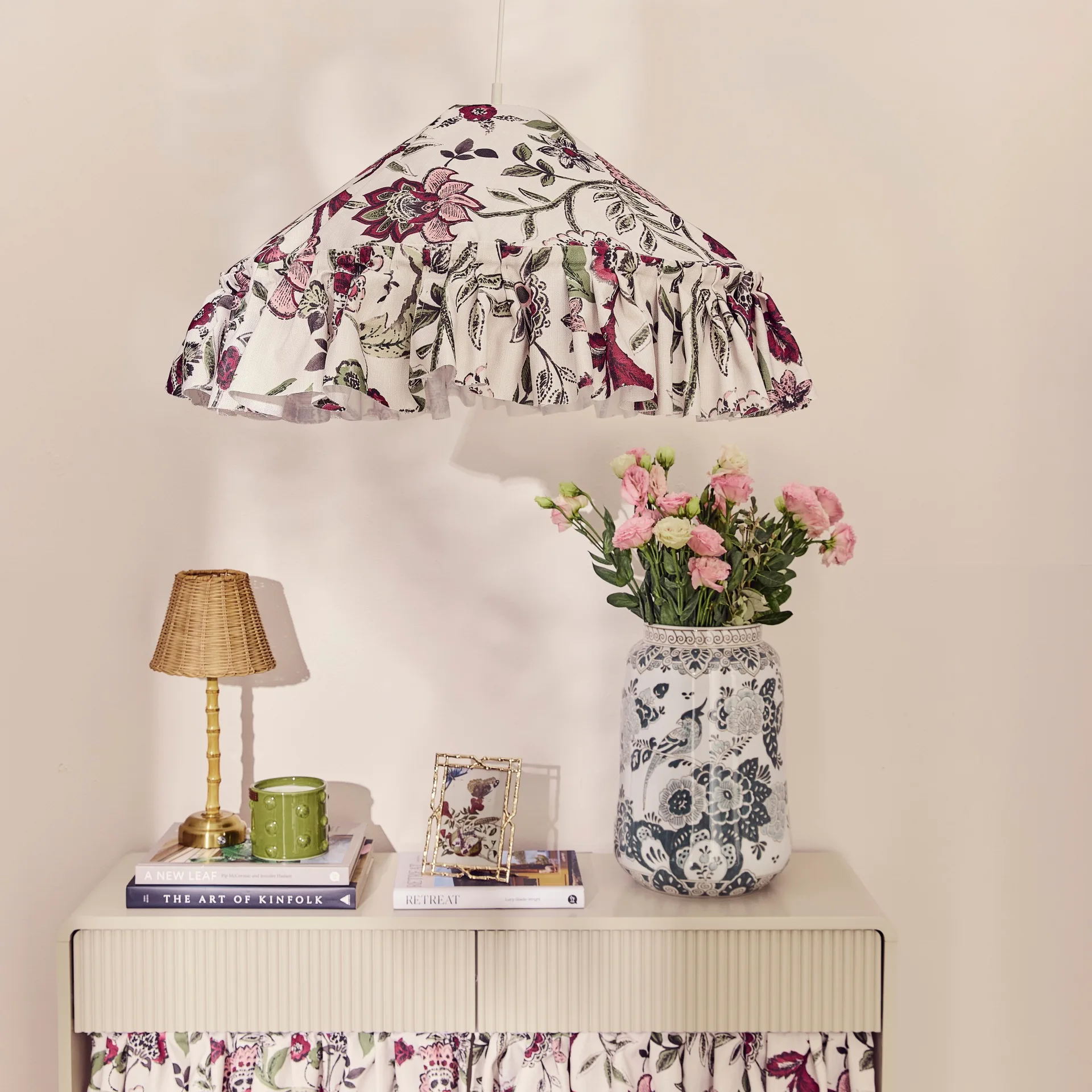 Floral fabric lightshade used as pendant light above beige console with fabric skirt and styled tabletop