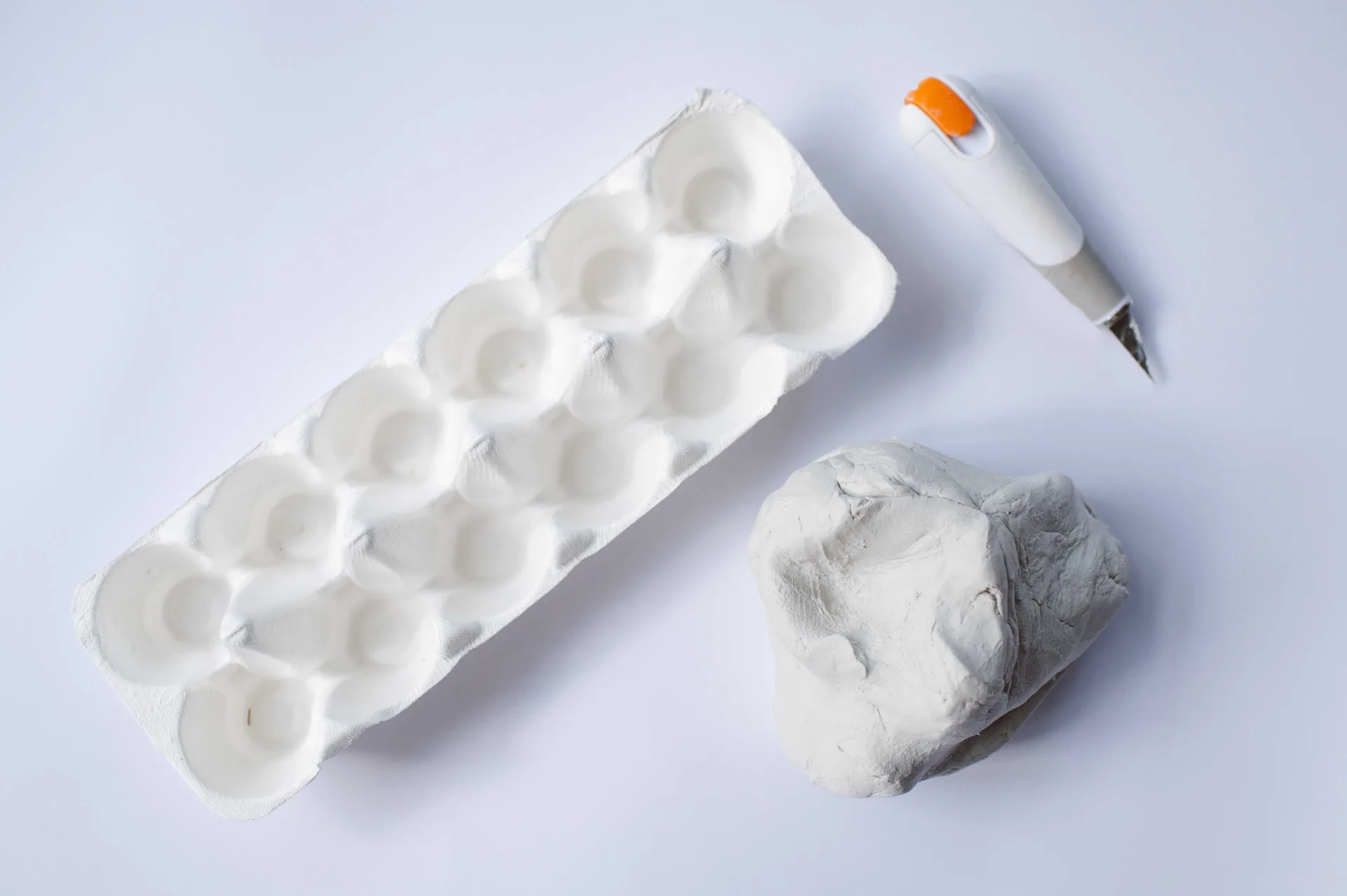 air dry clay next to cardboard egg carton and scalpel nearby