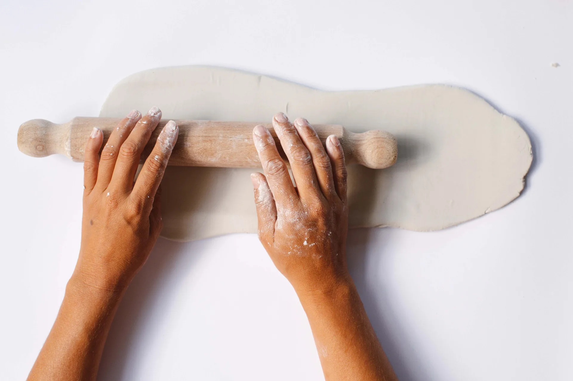 hands rolling out clay with rolling pin