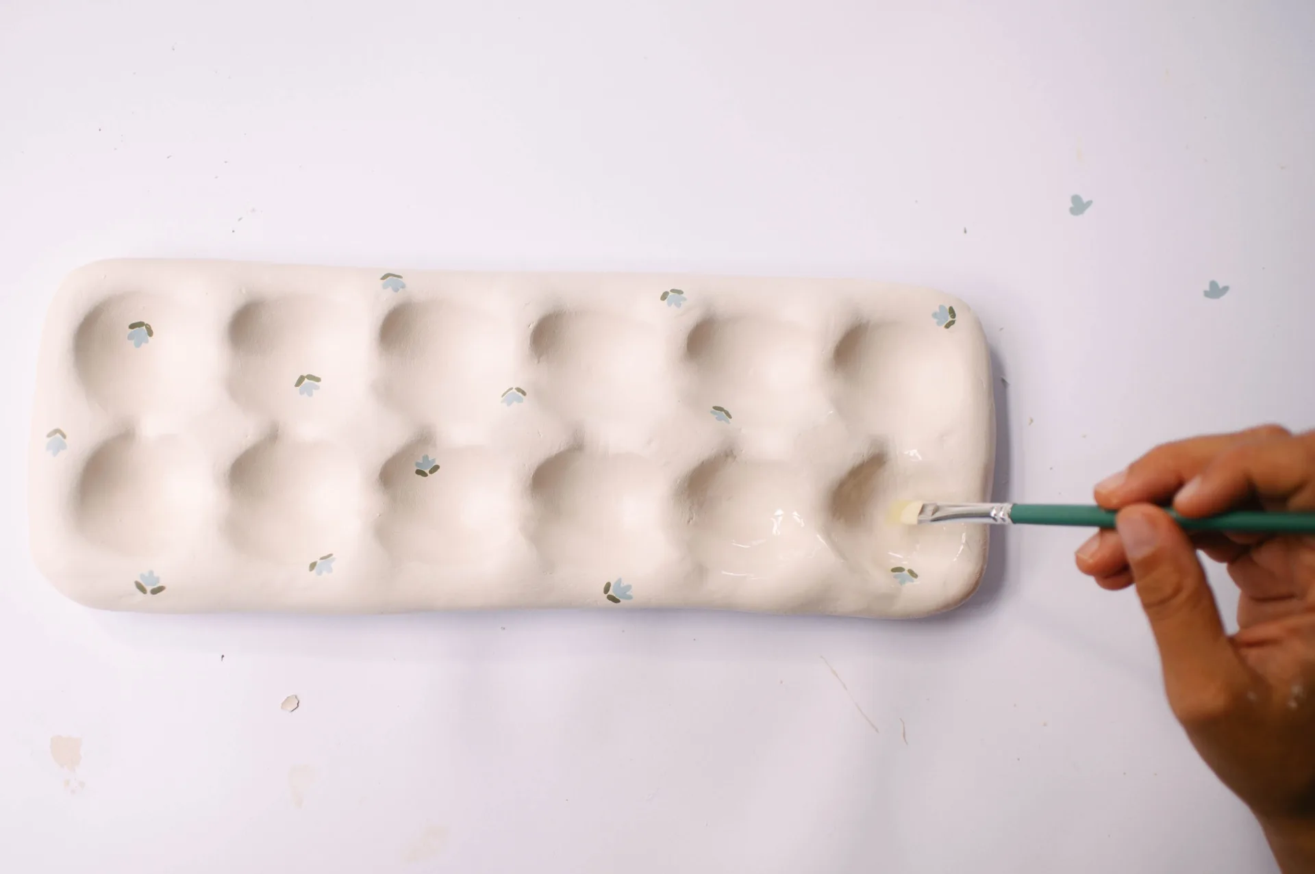 hand painting small blue tulips onto egg tray