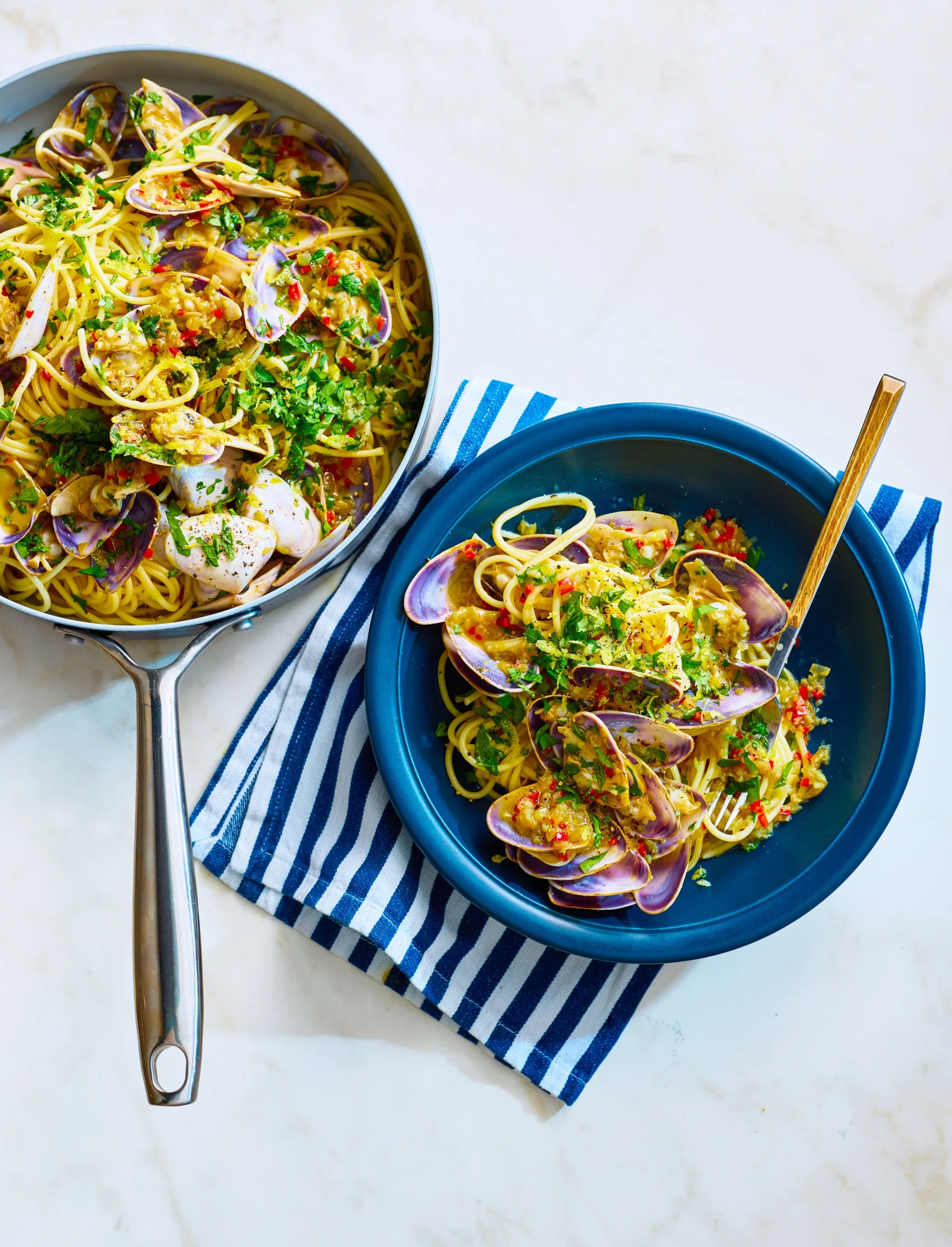matt moran spaghetti with pipis in blue bowl with fork sticking out and parsley on top and pan of spaghetti on the side