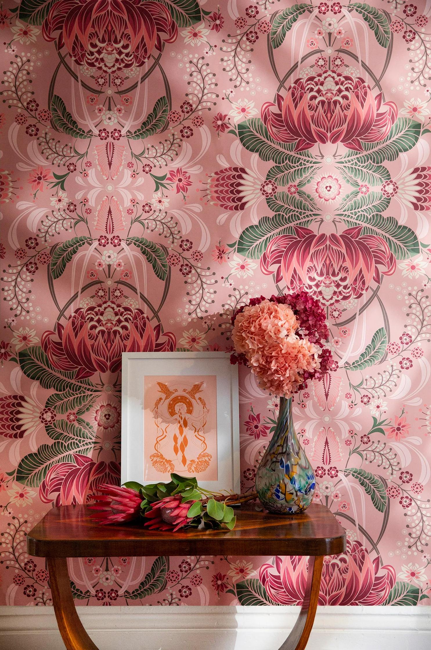 Pink and green Milton and King floral wallpaper with a rosewood side table and vase with flowers