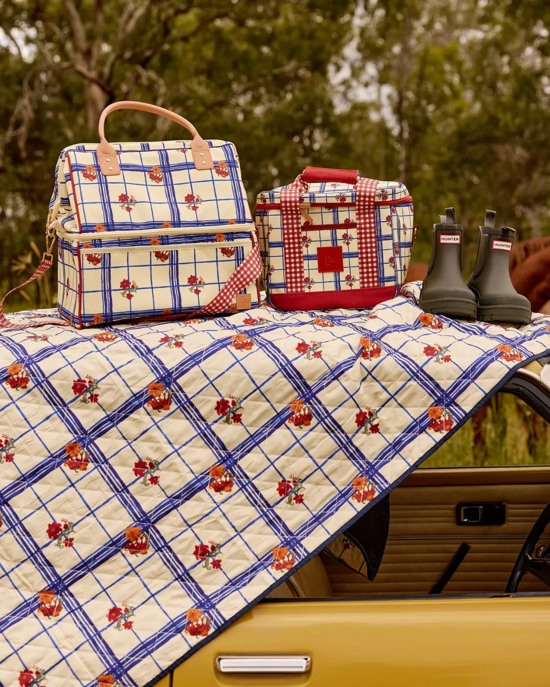 The Gatherer Picnic Rug from Somewhere Co, laid across the hood of a bright yellow car
