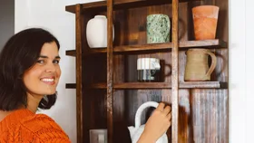 DIY expert and creator Geneva Vanderzeil with homemade timber display shelves in a grid pattern with ceramics.jpg
