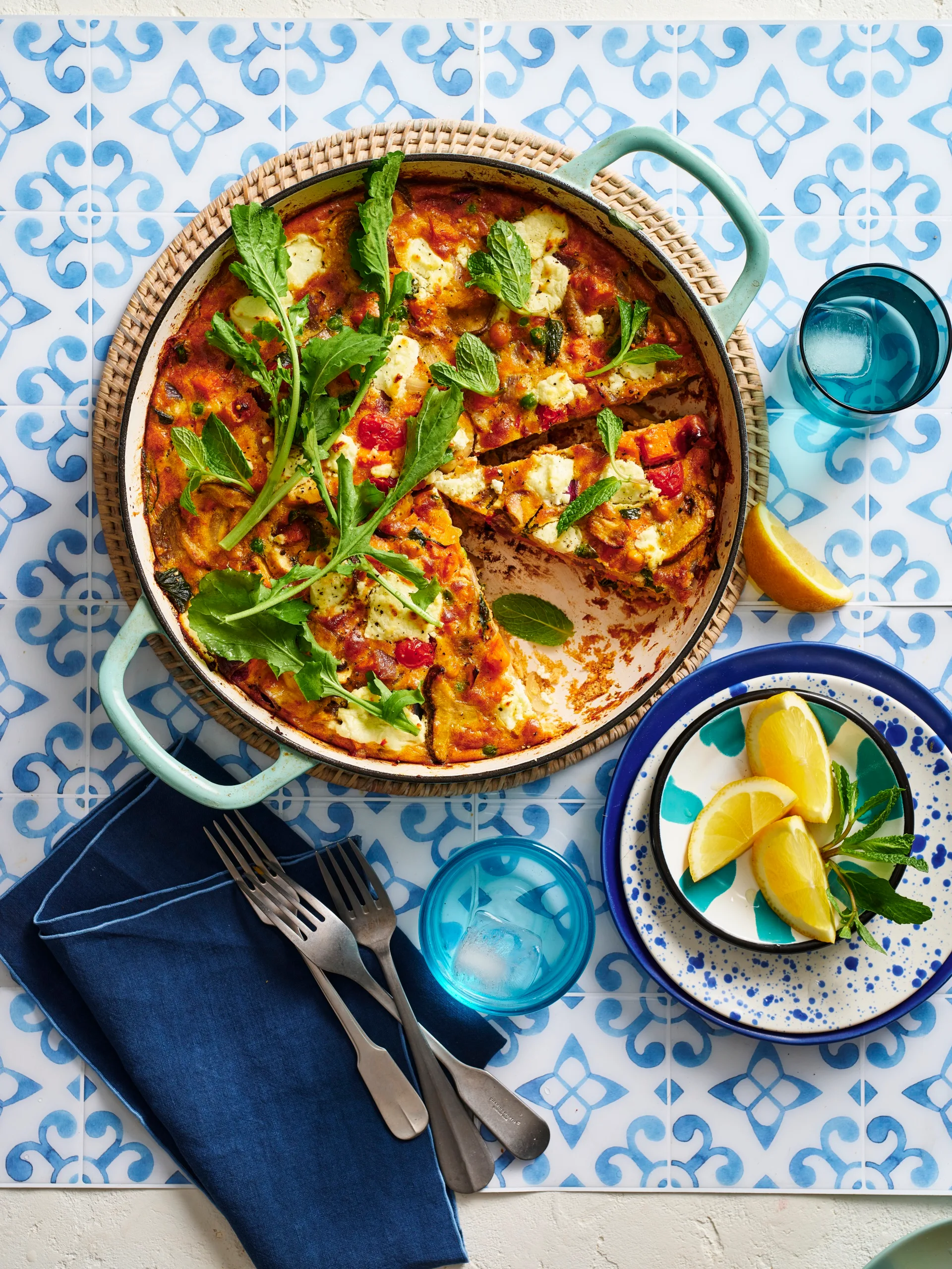 colin's vegetable frittata with greens sprinkled on top in round blue dish with handles