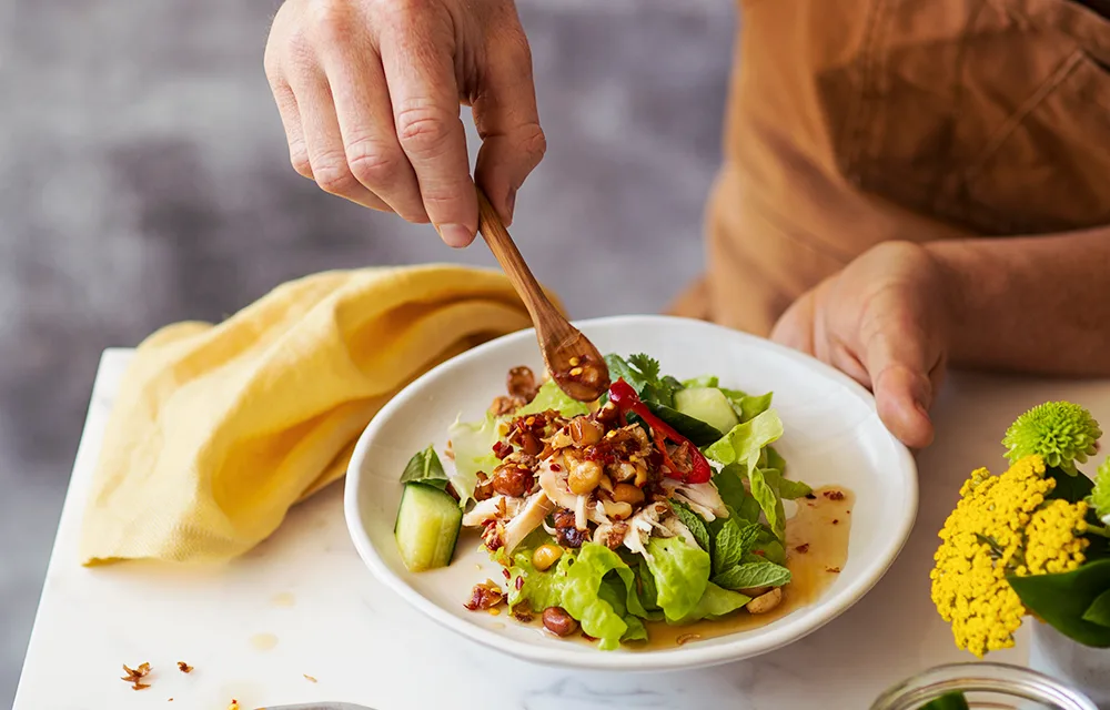 chicken salad with lettuce and pickled cucumber spoon being held dipping into it