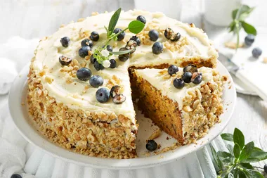 lemon and walnut cake with blueberries on top and nuts crusted on the side