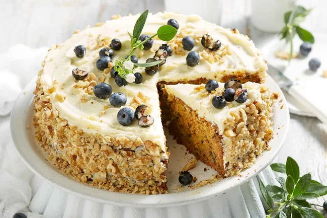 lemon and walnut cake with blueberries on top and nuts crusted on the side