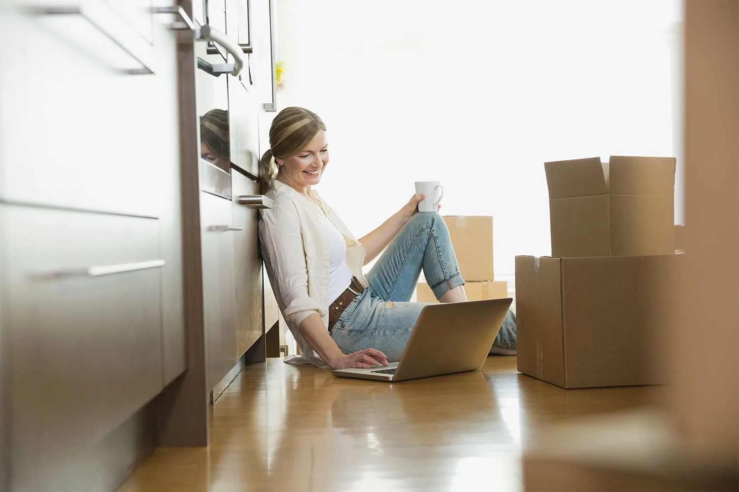 Woman sitting in kitchen with moving boxes