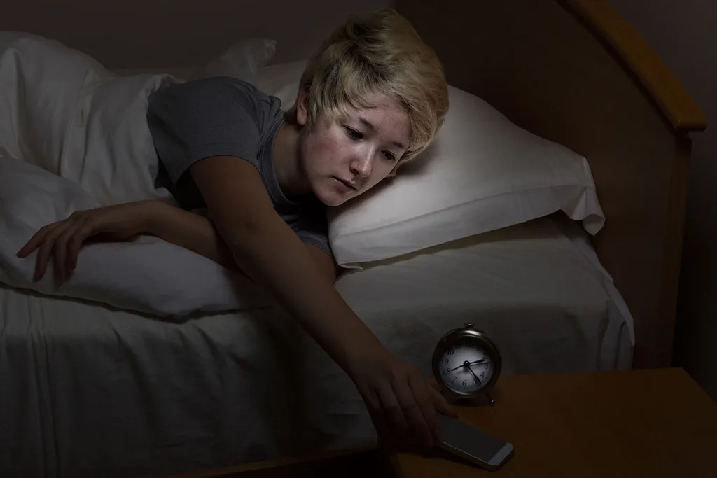 Woman in bed looking at alarm clock
