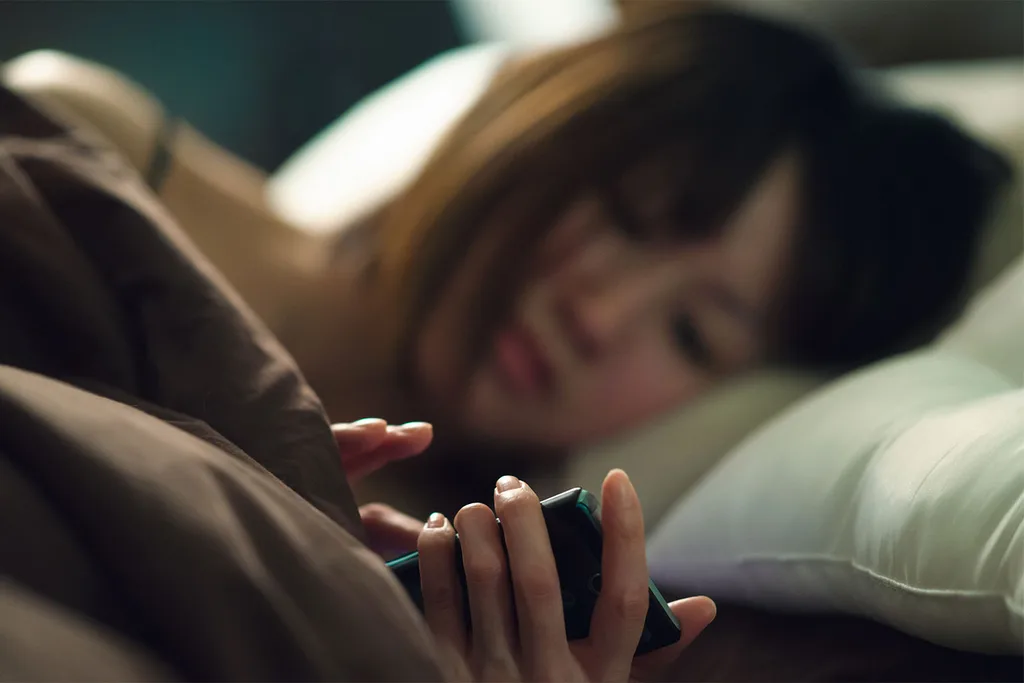 Woman in bed looking at mobile phone