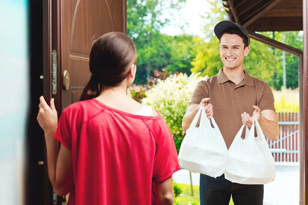 Man delivering takeaway food to woman at door.